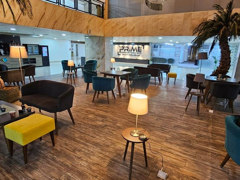 Modern communal lounge at Ground Floor, Building No. 93, Queen Nour Street with teal armchairs and wooden floors.