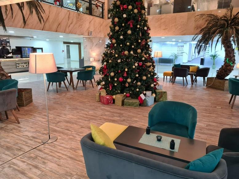 Communal lounge at the Housing Bank Complex featuring a tall decorated tree and teal armchairs.
