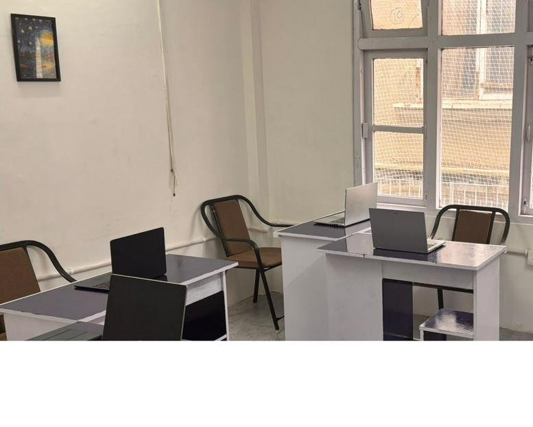 Workspace at 1st floor, Chauhan Niwas, Khalini with several white desks and black laptops.