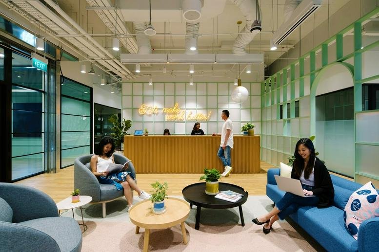 Spacious reception and lounge at China Square Central, 18 Cross Street with wooden desk and blue velvet sofa.