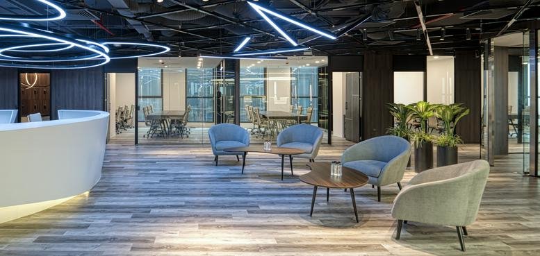 Modern reception and lounge at Coninco Tower with curved front desk and blue armchairs.