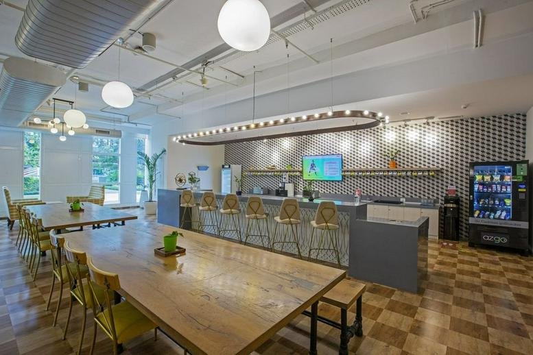 Spacious communal cafeteria at COWRKS BKC, Equinox Tower 4 with long wooden tables and a modern bar.