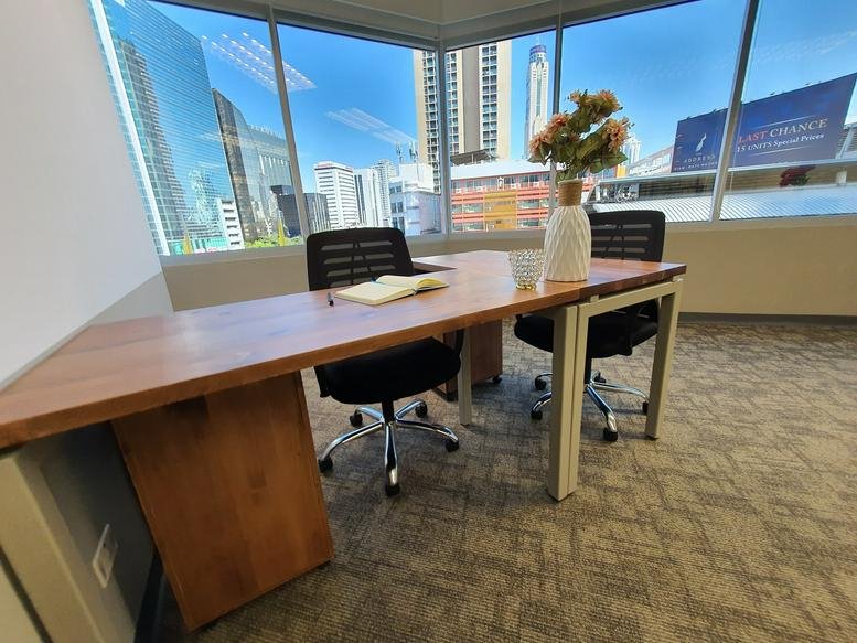 Two-person private office suite with corner windows overlooking the city skyline.