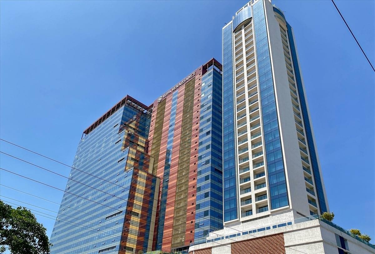 Full view of the towering glass exterior of Rupa Renaissance against a blue sky.