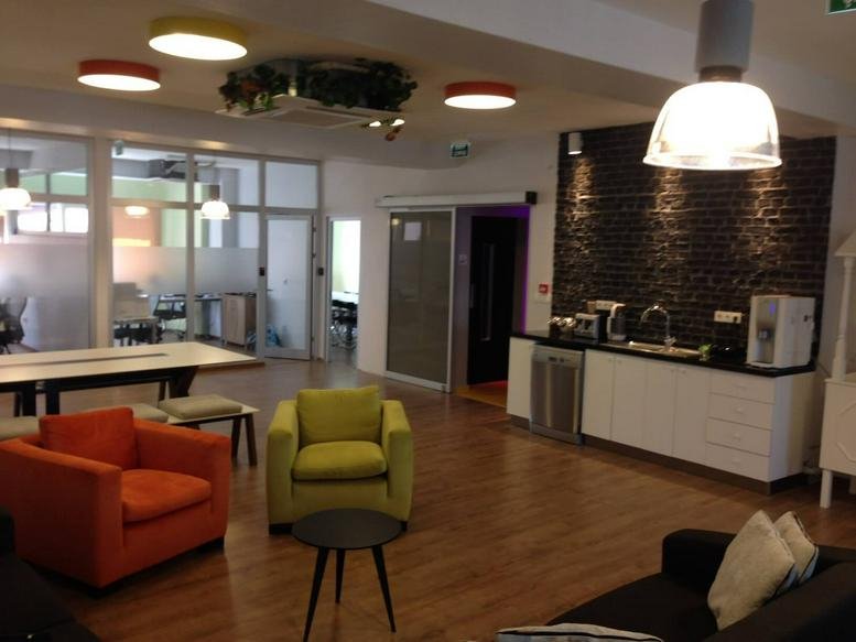 Spacious communal lounge at Kamara DOME Building with colorful armchairs and a modern kitchen area.