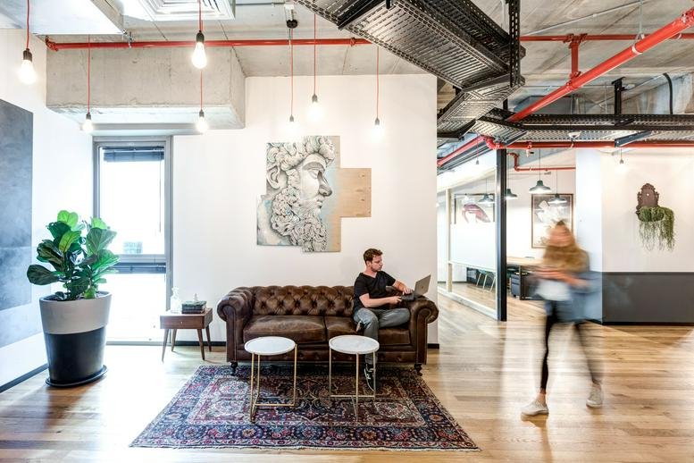 Spacious lounge at Derech Menachem Begin 11, Ramat Gan featuring a leather sofa and industrial ceiling.