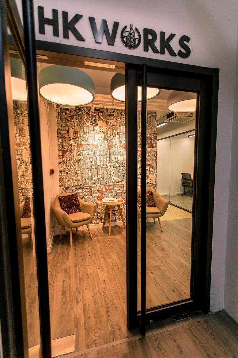 Main entrance of HK WORKS at Derrick Industrial Building with sliding glass doors and warm lighting.