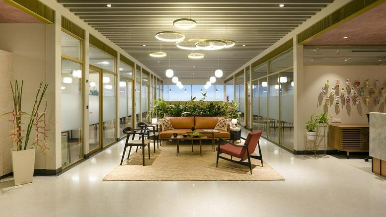 Bright, open reception area with stylish ring pendant lights and glass-walled private offices.