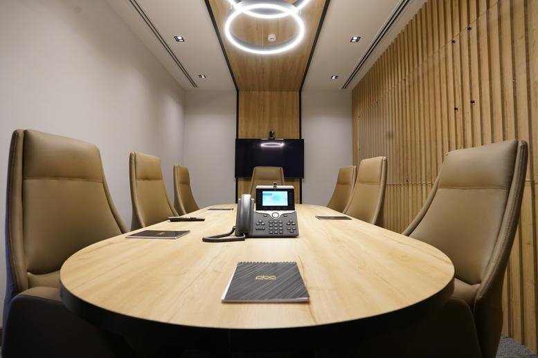 Sleek boardroom at District Building B, 6th Floor with an oval wooden table and leather seating.