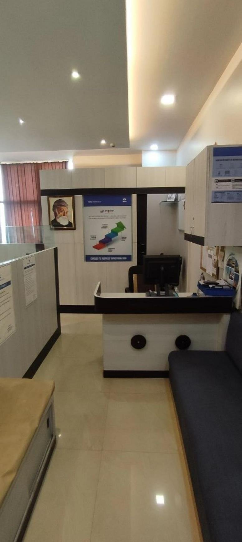 Bright reception desk at Merlin Matrix with professional signage and a comfortable blue sofa.