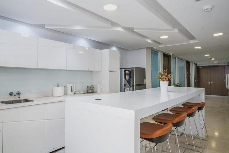 Contemporary white kitchen and break area with a long breakfast bar and stools.