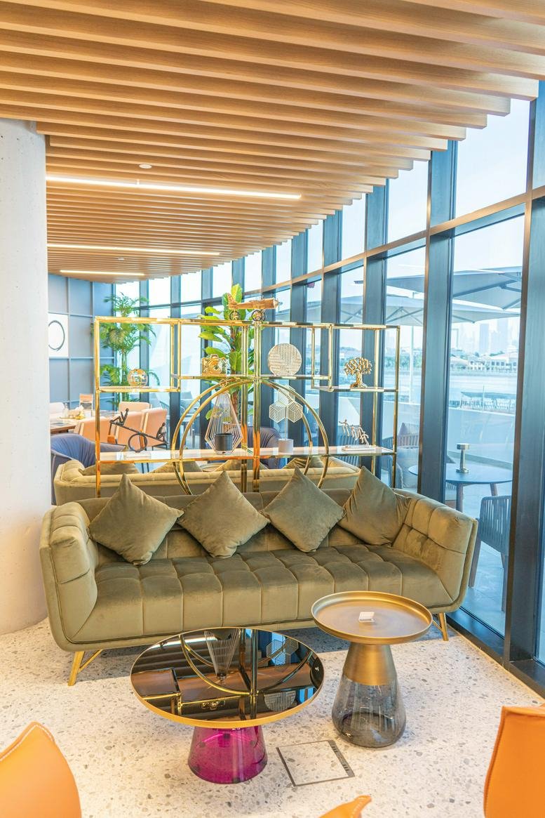 Dubai Chambers New Extension Building lounge with a plush olive green sofa and gold-accented shelving.