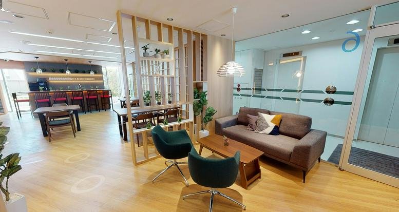 Spacious communal lounge at Ebisu Green Glass Building with velvet chairs and a wood-slat partition.