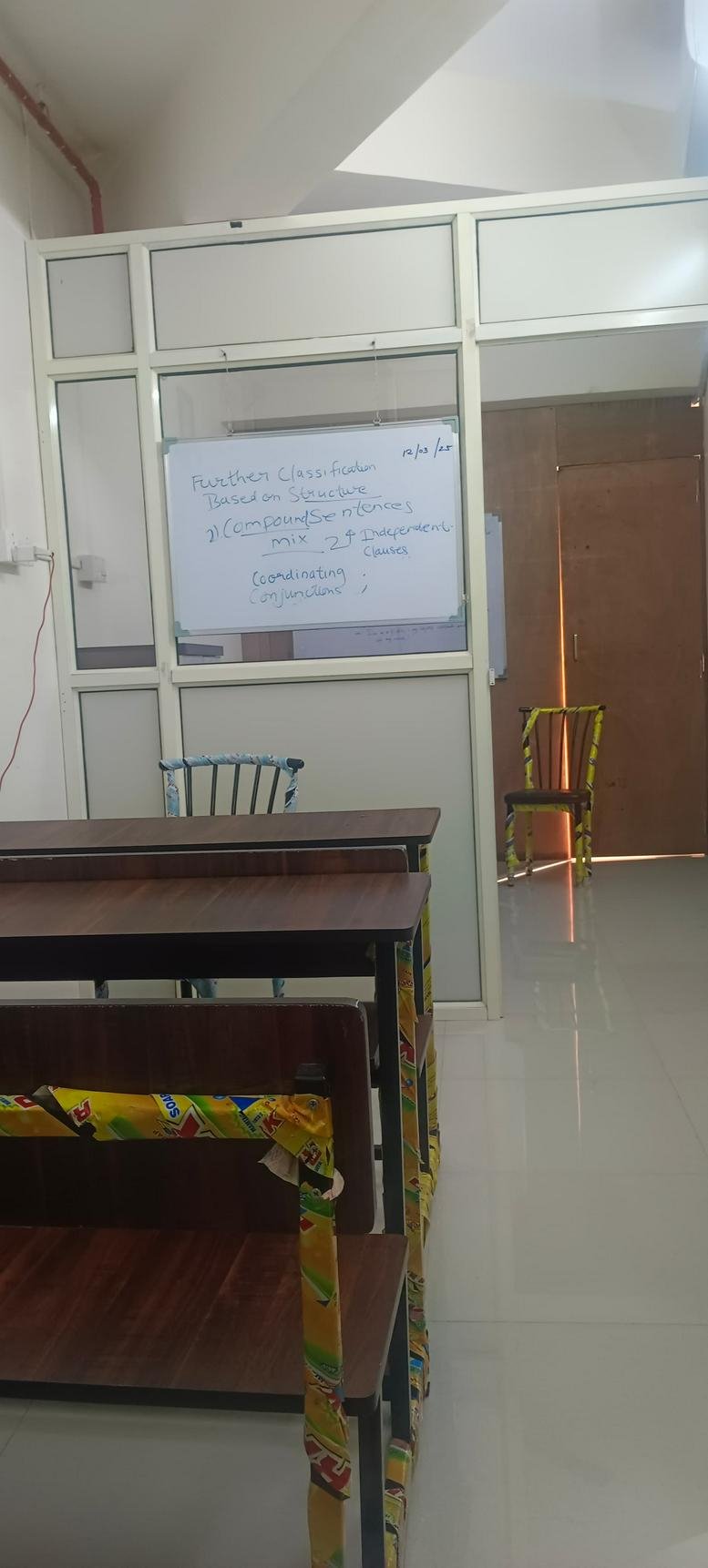 Classroom interior featuring a whiteboard with lesson notes and rows of wooden desks.