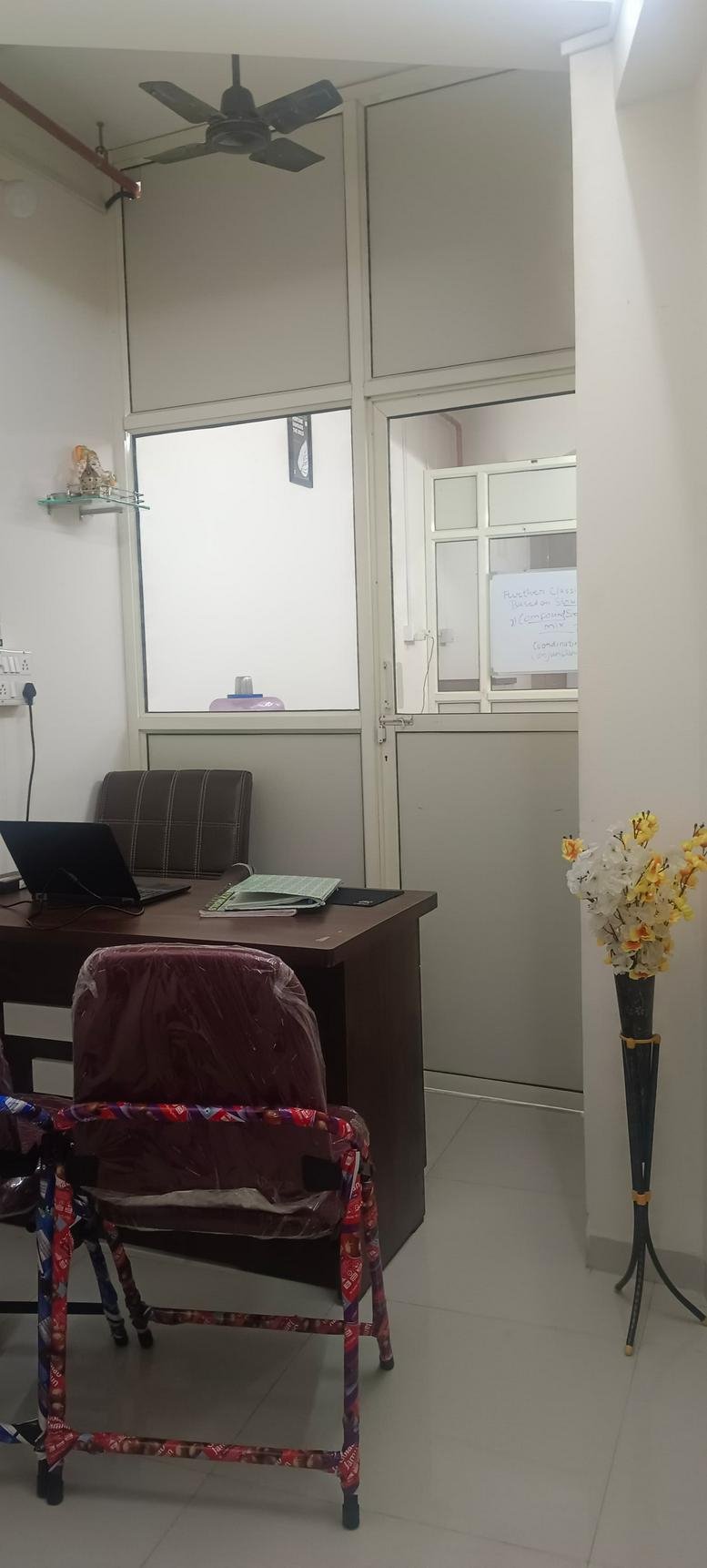 Private office suite with a dark wood desk, laptop, and a decorative vase of flowers.