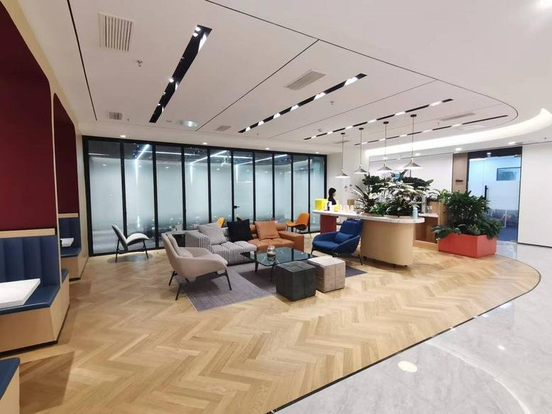 Spacious communal lounge at Fengli Mansion featuring modern seating, wood flooring, and a glass-walled meeting room.