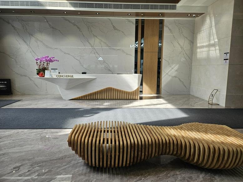 Modern lobby of First Group Centre at 23 Wang Chiu Road with marble walls and a unique wooden bench.