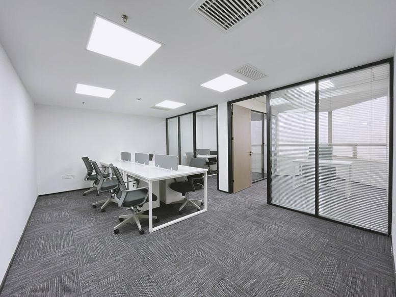 Spacious open-plan workspace at Fudu Building with white desks and glass-partitioned private offices.