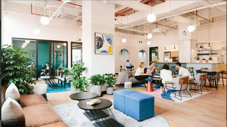 Spacious sunlit lounge at Gangnam Station II, 7 Teheran-ro 5-gil, featuring plants and blue ottoman seating.