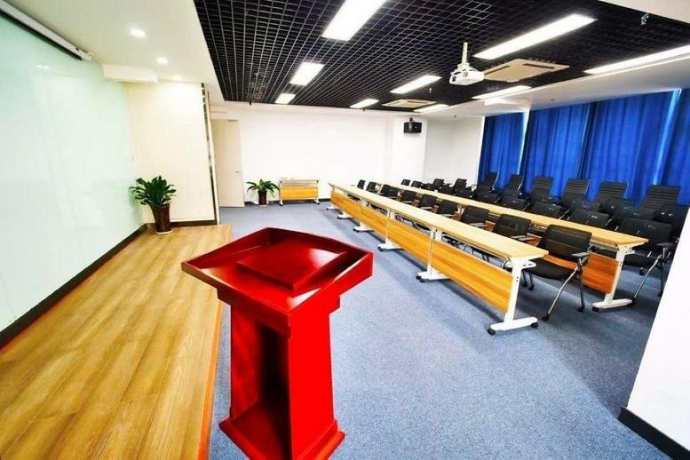 Spacious presentation room at New Century Building with a red wooden podium and rows of desks.