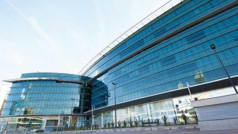 Exterior view of the curved glass-facade building at Level 6, Gate D on Olaya Street.