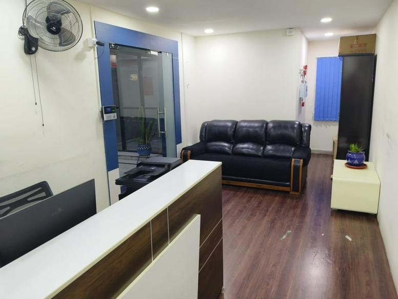 Reception area at Greenlands Road, Kundanbagh Clolny Bagumpet with a black leather sofa and wooden flooring.