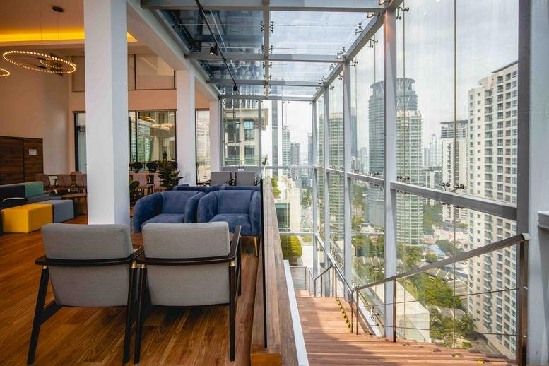Spacious indoor-outdoor lounge area at GTower with floor-to-ceiling glass walls and city skyline views.
