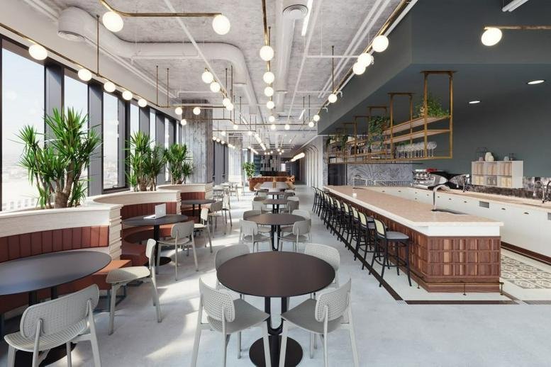 Spacious communal dining area and café at Raanana Business Park with modern lighting and greenery.