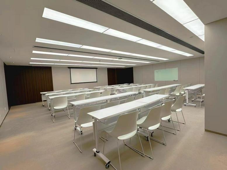 Spacious lecture-style meeting room at Haikou Zhongguancun Information Valley Innovation Center with rows of white desks.