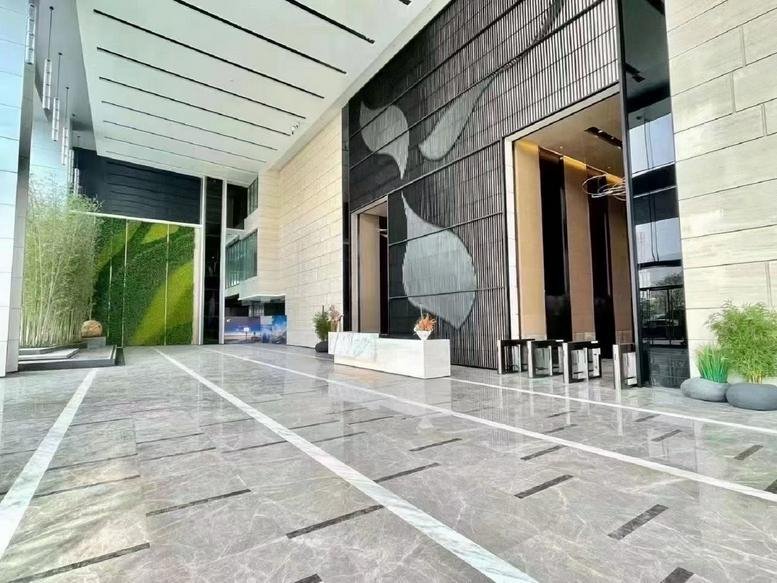 Spacious modern lobby with polished marble floors and a large leaf motif on a dark feature wall.