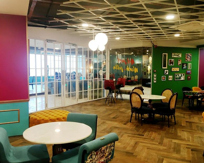 Lounge area with teal armchairs, a wooden herringbone floor, and vibrant green wallpaper.