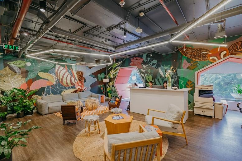 Spacious reception and lounge at Building 25T2 with colorful murals, wooden floors, and modern furniture.