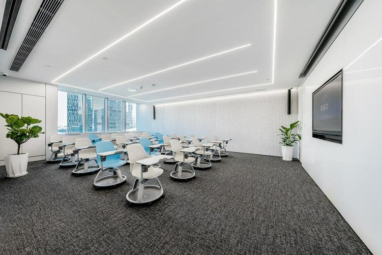 Spacious seminar room at IEC Vanke Centre with rows of ergonomic tablet chairs and bright window views.
