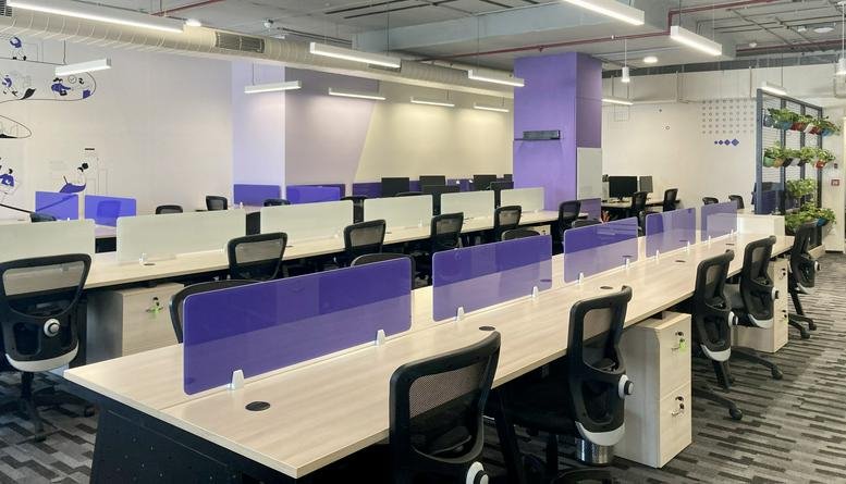Bright open-plan workspace at iLabs Centre with rows of desks and purple privacy dividers.