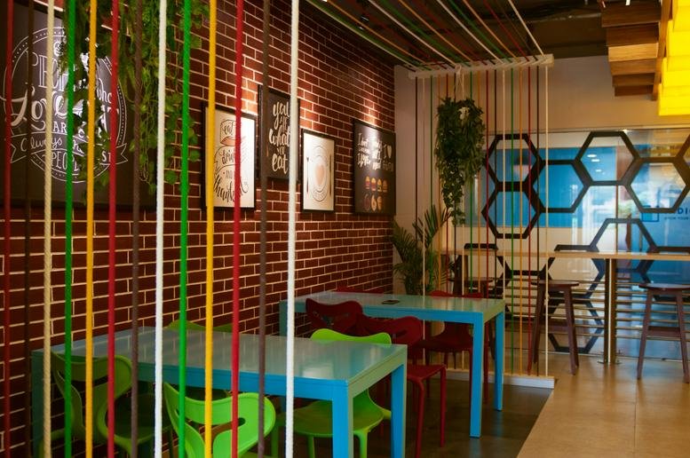 Vibrant communal breakout area at Indiqube Amber, Domlur, Dell India, Bangalore with brick walls and colorful furniture.