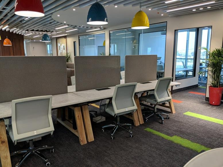 Spacious open-plan workspace at IT Tower, Plot 29, Sec 142, Noida featuring modern desks and vibrant pendant lights.