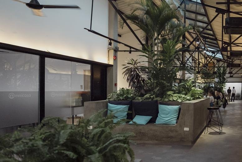 Spacious communal lounge at the Itaxa Building featuring a sunken seating area with blue pillows and tall palm trees.