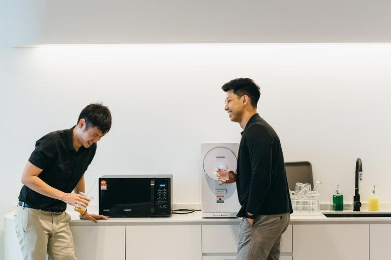 Communal break area with a kitchen counter, microwave, and people chatting at Southern Tower First Subang.