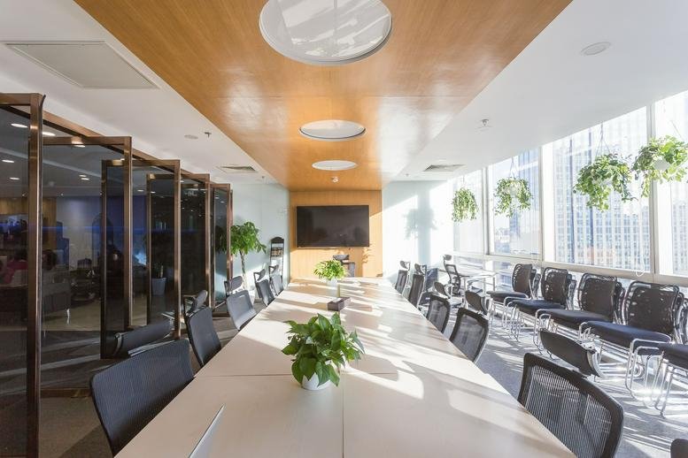 Spacious boardroom at Soho Nexus Center with wood-paneled ceilings, a long white table, and hanging plants.