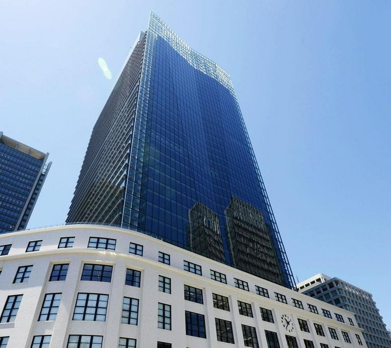 Low angle exterior view of the modern glass and stone JP Tower in Tokyo.