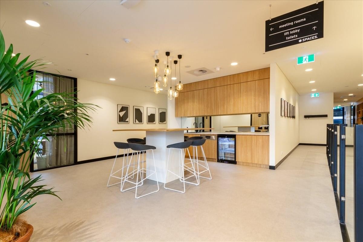 Bright communal kitchen area with a high white marble island and light wood cabinetry.