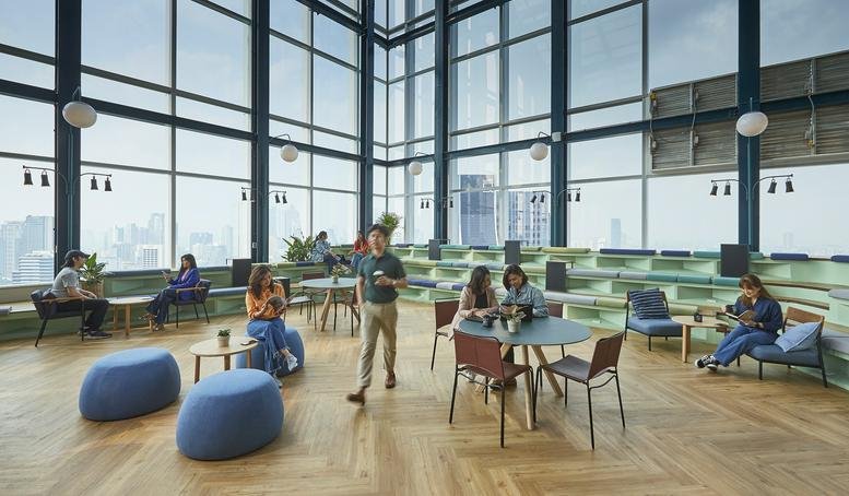 Spacious coworking lounge at JustCo at Mitrtown Office Tower featuring tiered seating and panoramic city views.