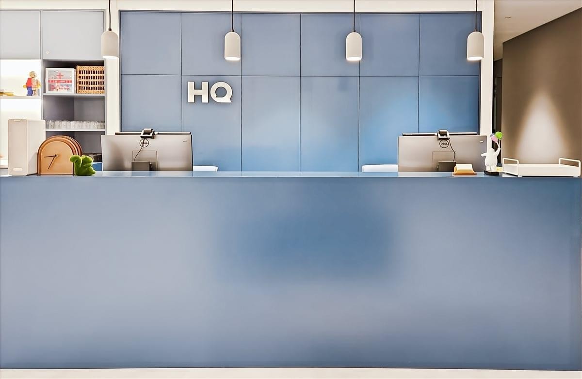 Reception desk at K11 Atelier, 728 King’s Road with sleek blue panelling and HQ branding.