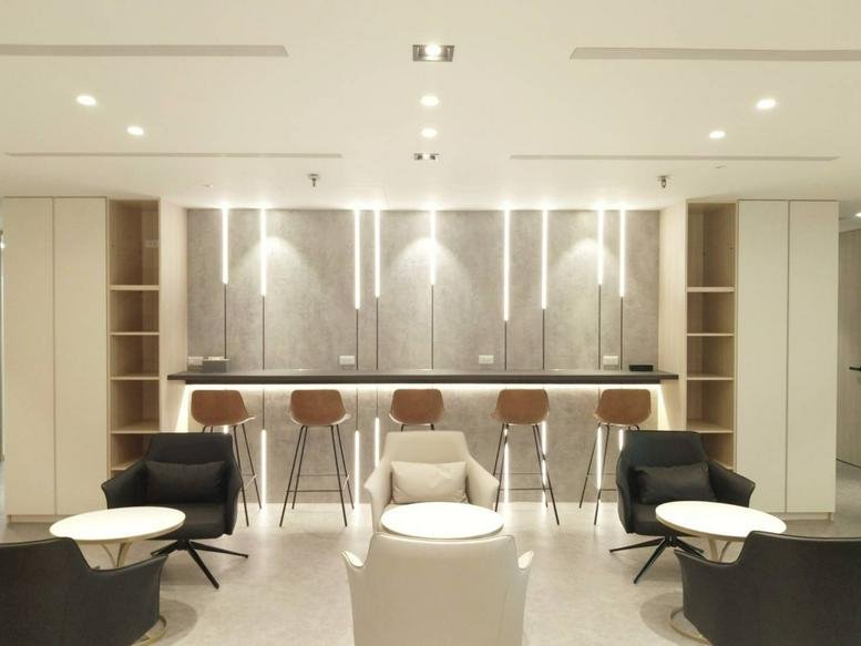 Modern communal lounge area with a breakfast bar, stools, and plush armchairs.