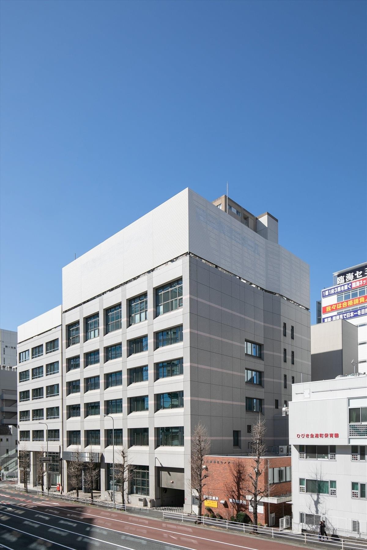 Exterior view of the multi-story grey facade of the Kinko Building under a clear blue sky.