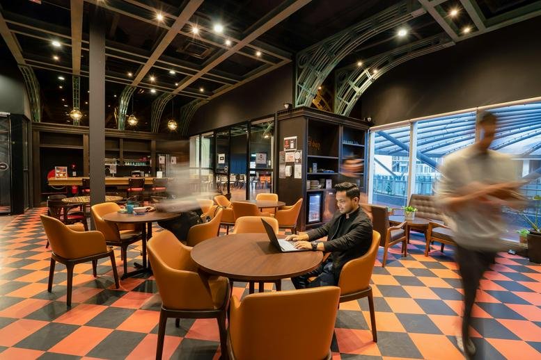 Vibrant coworking lounge with checkered flooring, round wooden tables, and arched architectural details.