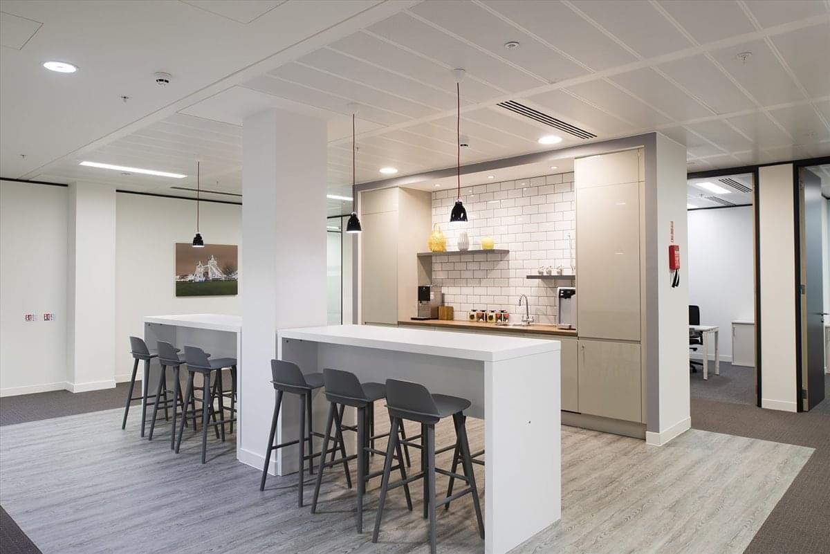 Spacious communal breakout area with white breakfast bars and grey stools at Kokuraekimae Hibiki Building.