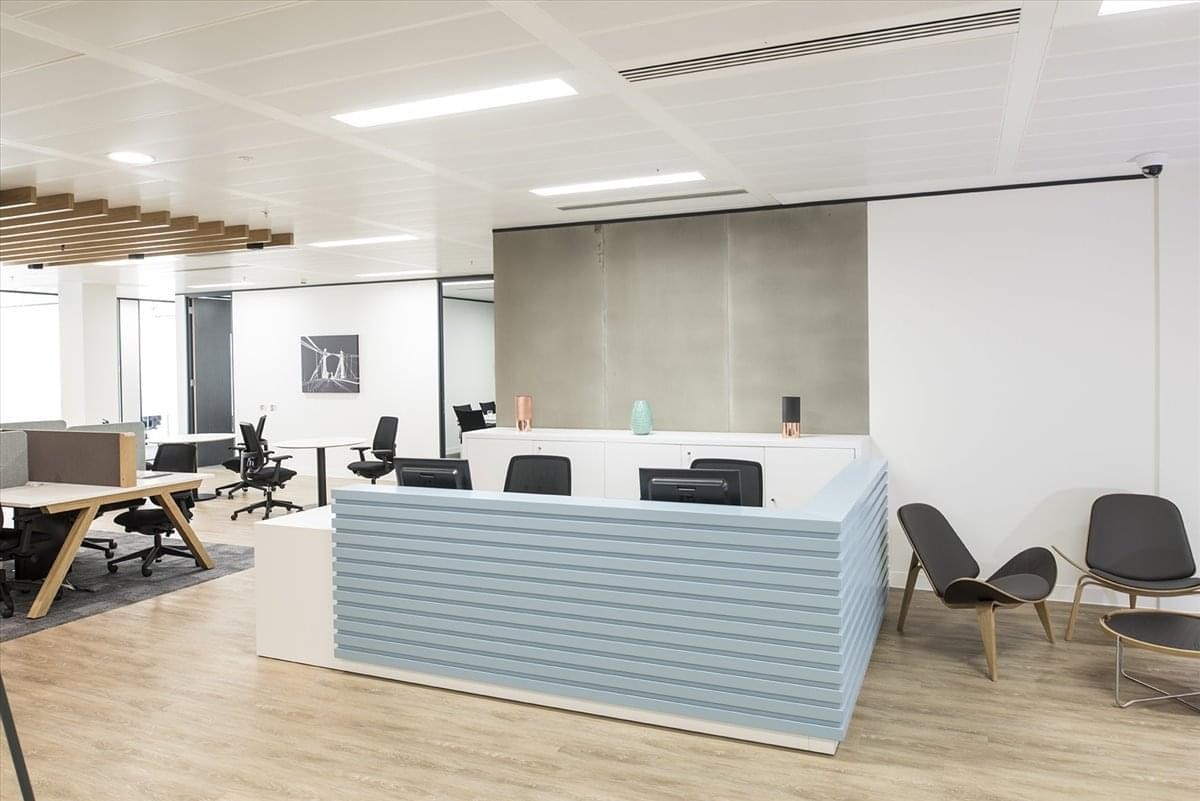 Contemporary reception area at Kokuraekimae Hibiki Building with a light blue slatted desk and lounge chairs.