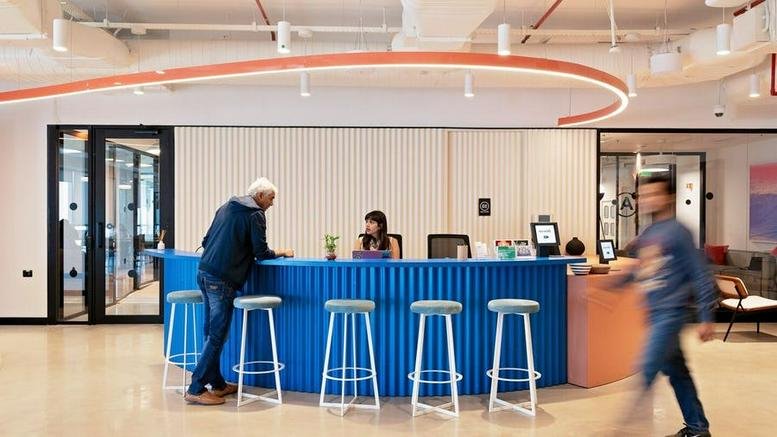 Modern reception area at Krishe Emerald, Laxmi Cyber City, Hyderabad featuring a blue corrugated desk and bar stools.