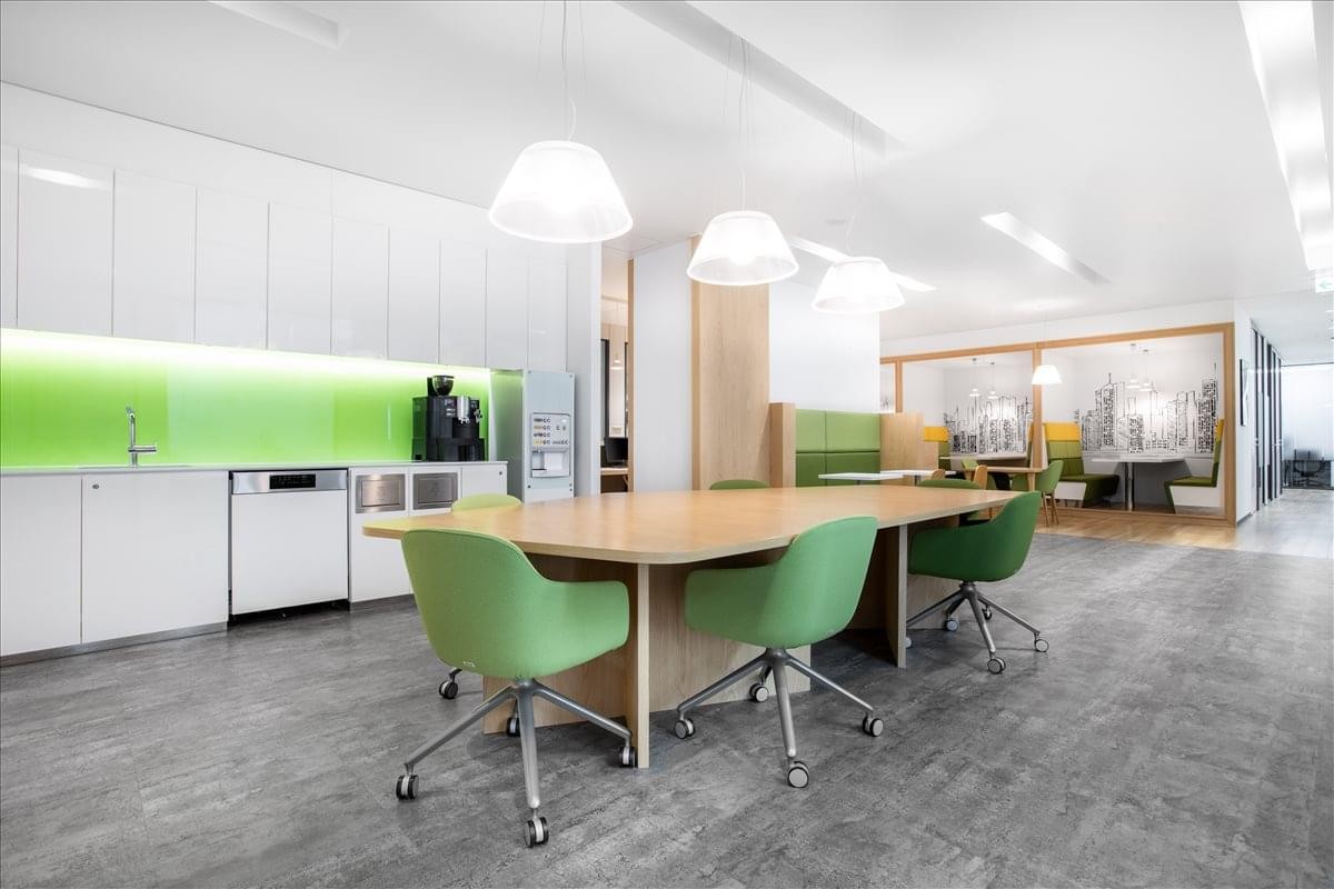 Spacious communal kitchen and dining area at Kurax Sendai 4F, 3-3-1 Ichibancho with green chairs and white cabinetry.